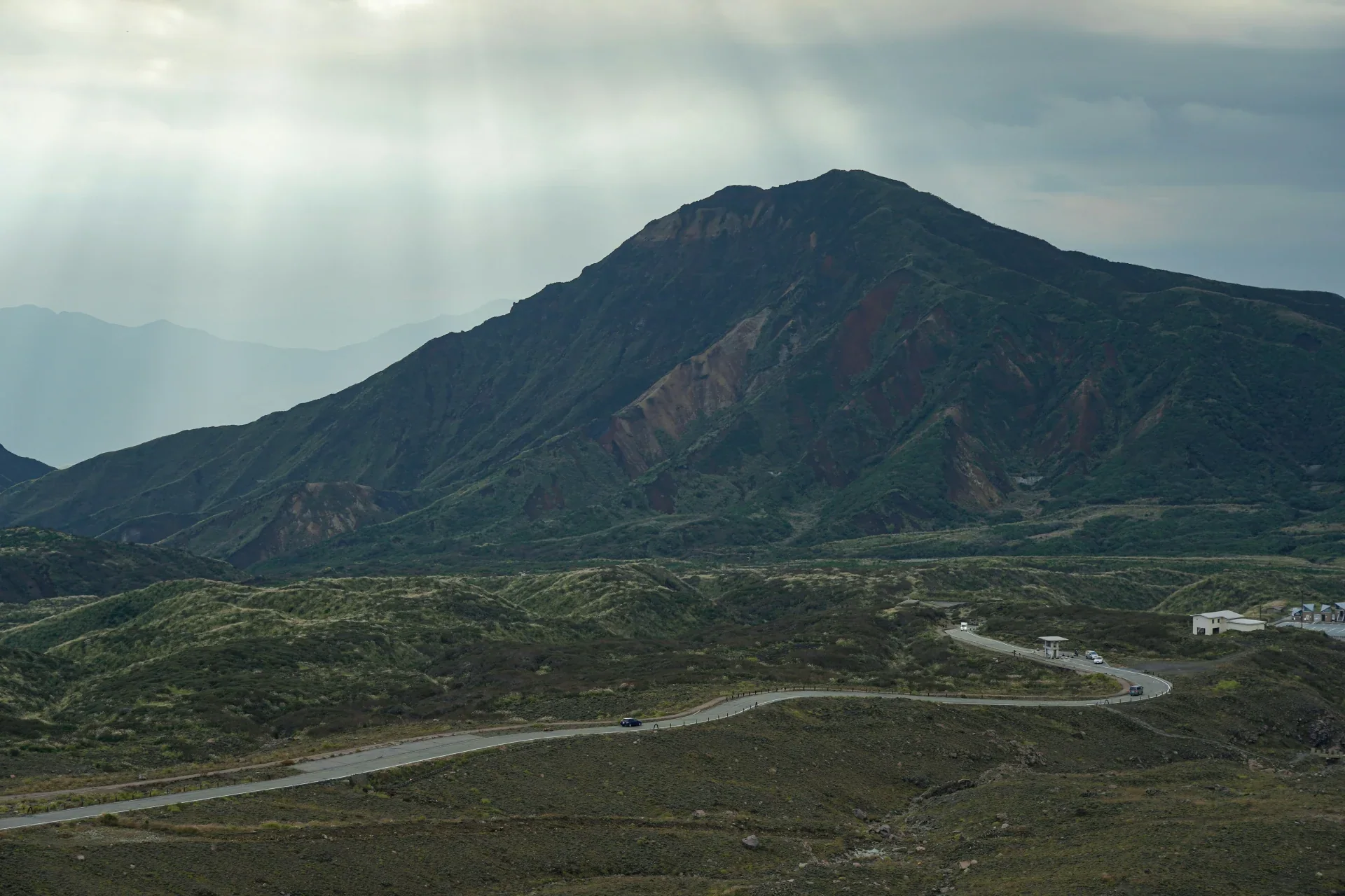 阿蘇山脈前的彎道路段，遠處山景與草坡清楚可見