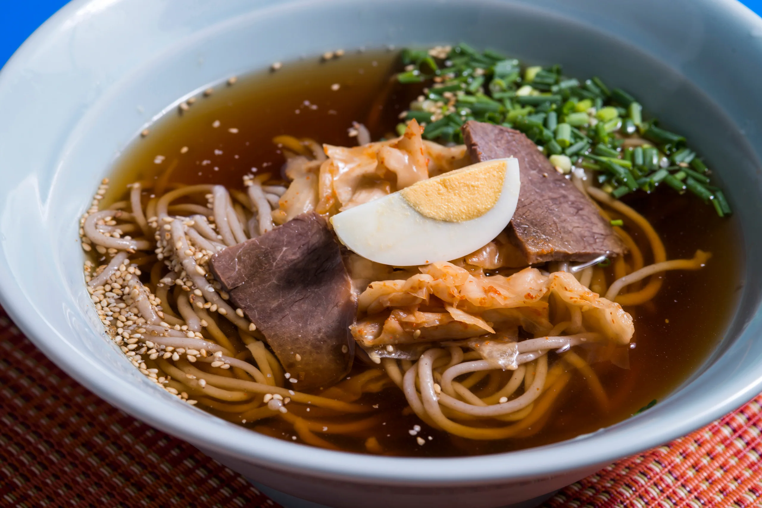 別府冷麵一碗冷湯麵，配有牛肉、泡菜、蔥花和雞蛋