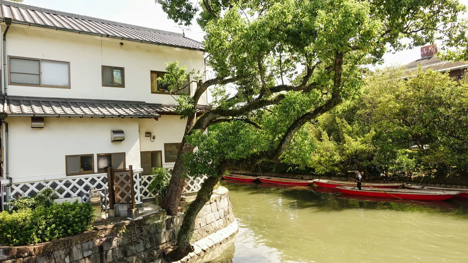 柳川堀割旁的老屋與紅色川下り小舟，船夫沿河岸水道慢慢前行