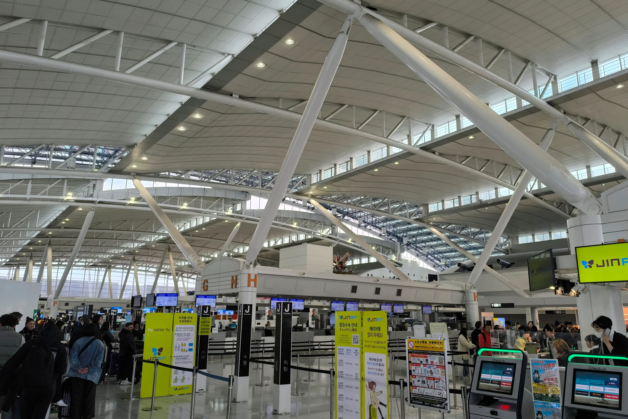 福岡機場國際線出發大廳，畫面可見航空公司報到櫃檯與自助報到設備