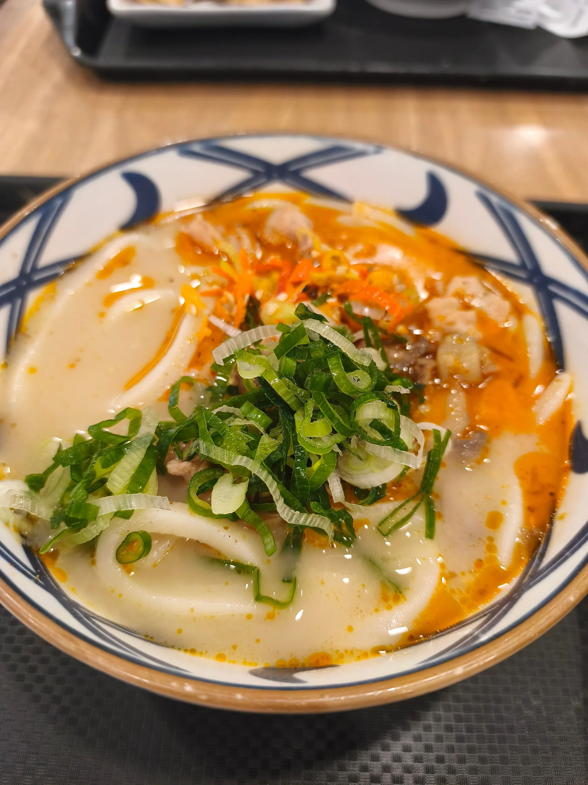 烏龍麵湯中配有蔥花、蔬菜和其他配料