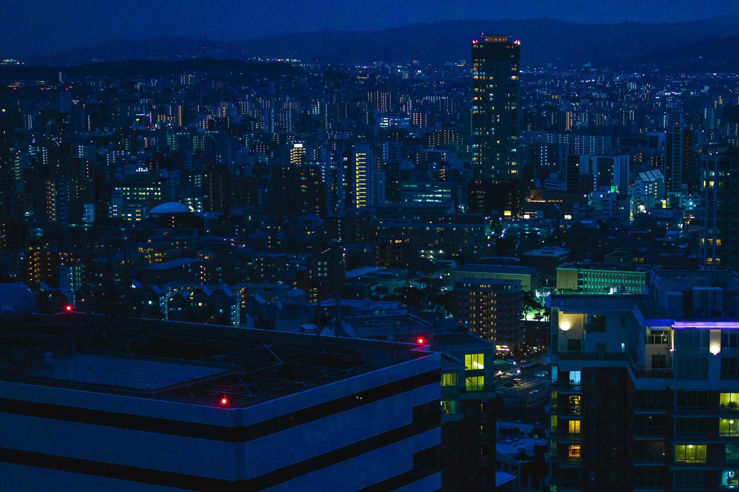 從福岡塔高處眺望的福岡市夜景，遠處樓宇燈光亮起