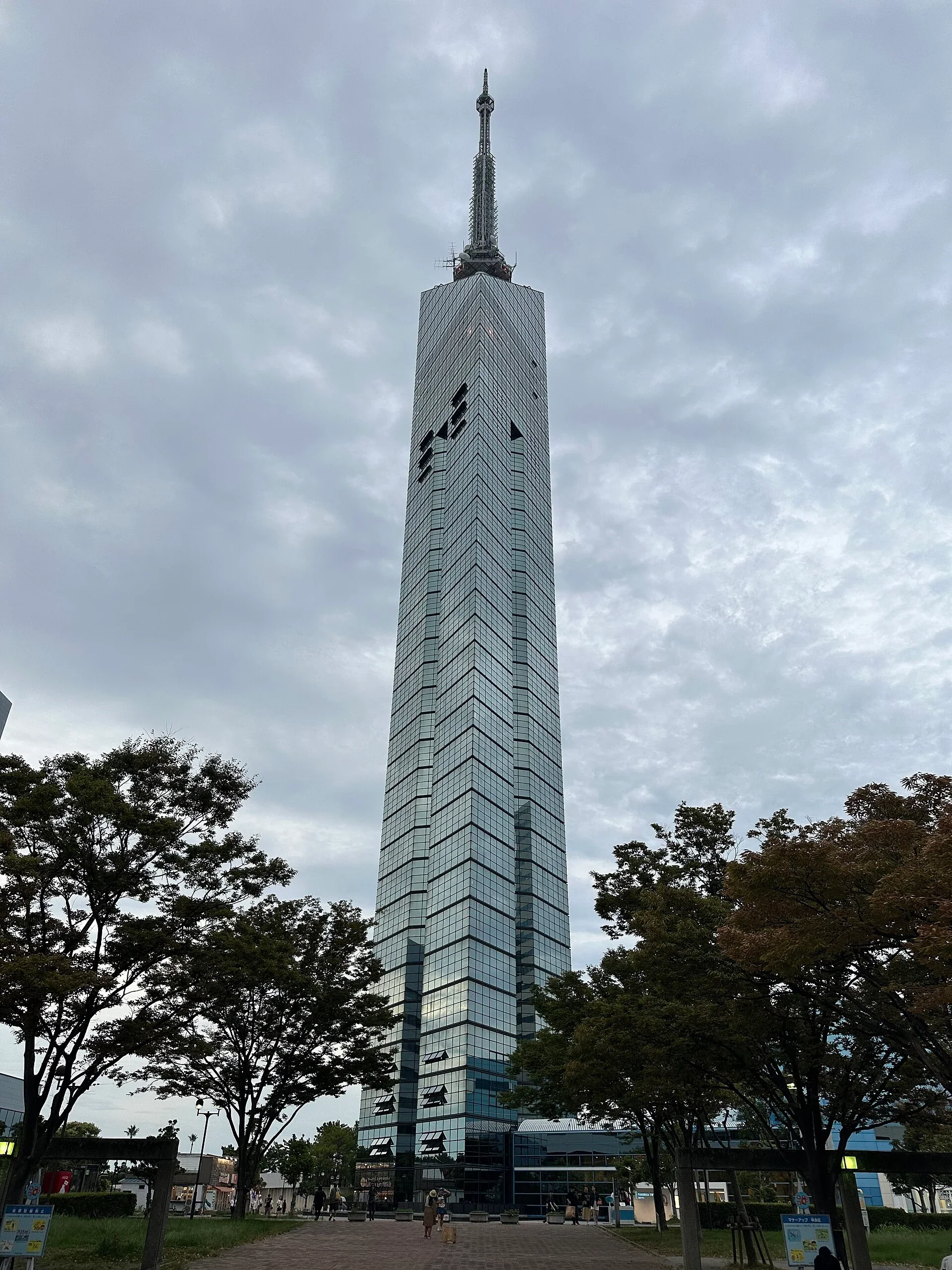 福岡塔在百道濱樹林間的塔身全景