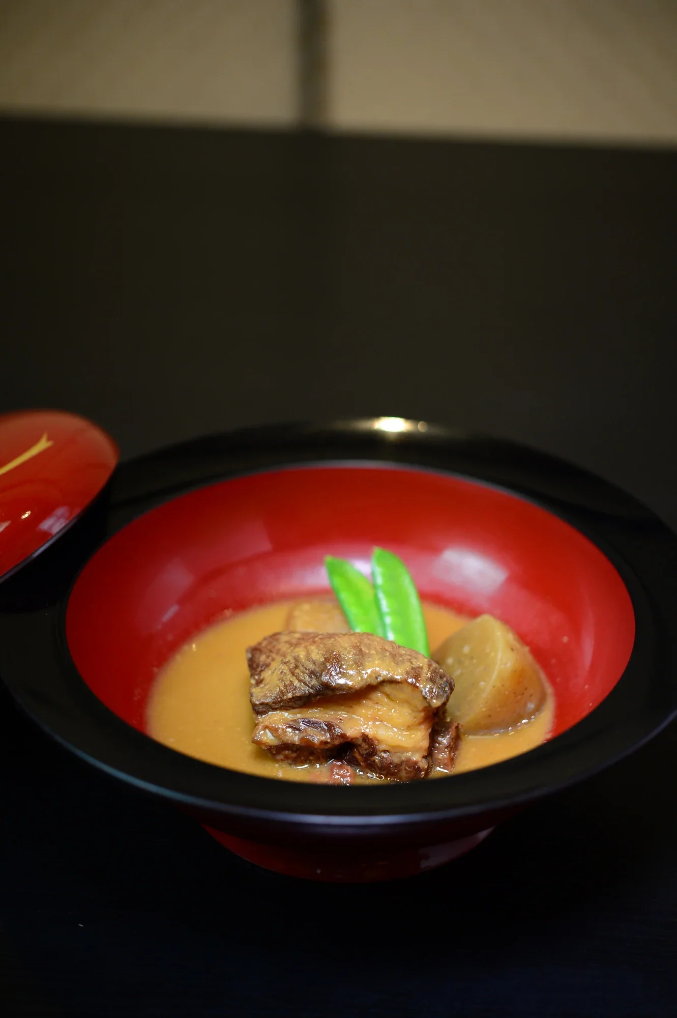鹿兒島豚骨味噌煮，帶骨豬肉與根菜盛在紅色漆碗中