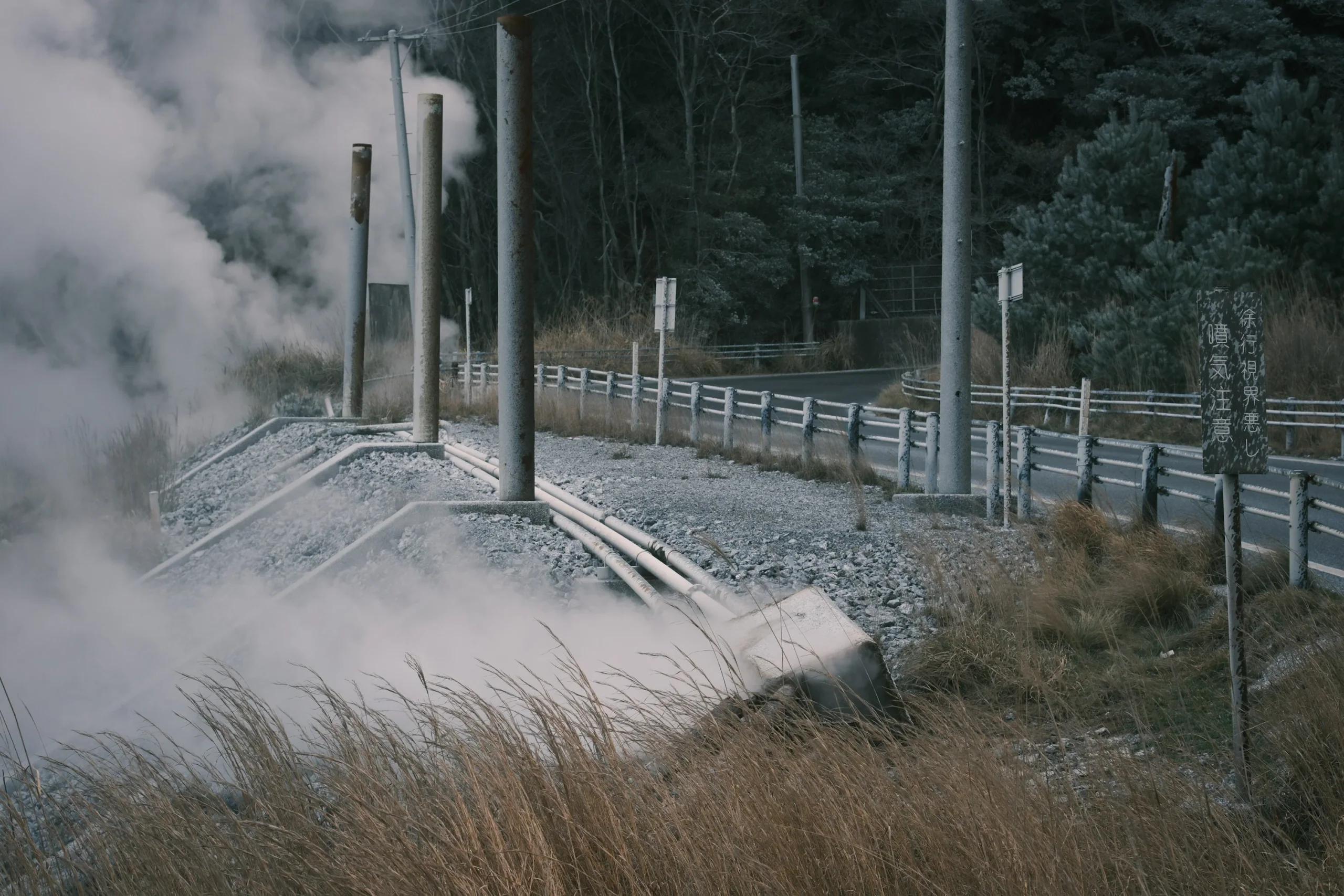 霧島山區道路旁的地熱蒸氣由地面升起,旁邊可見護欄和管線