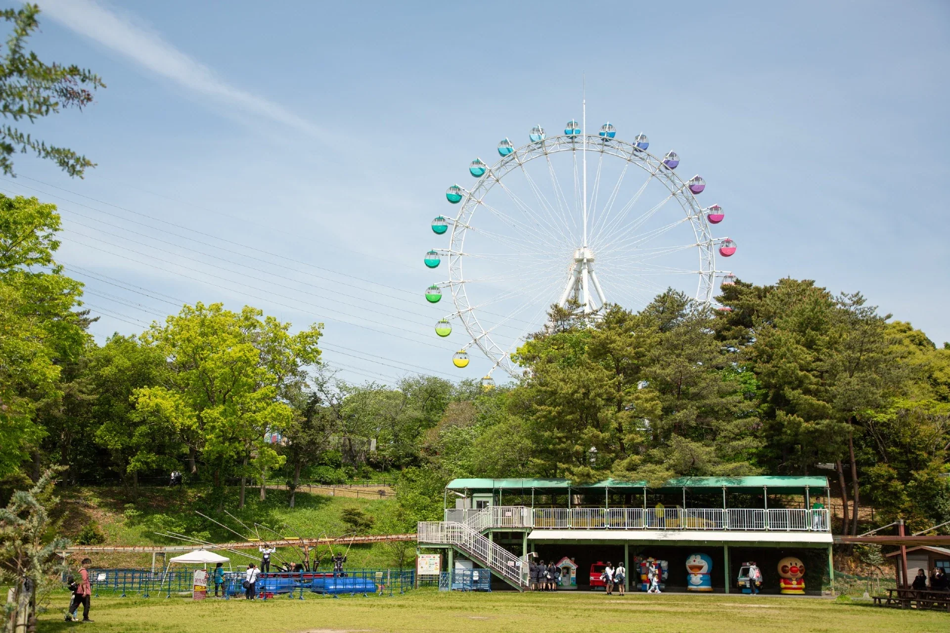 到津之森公園內的摩天輪、樹木與遊樂設施，遠處有遊客