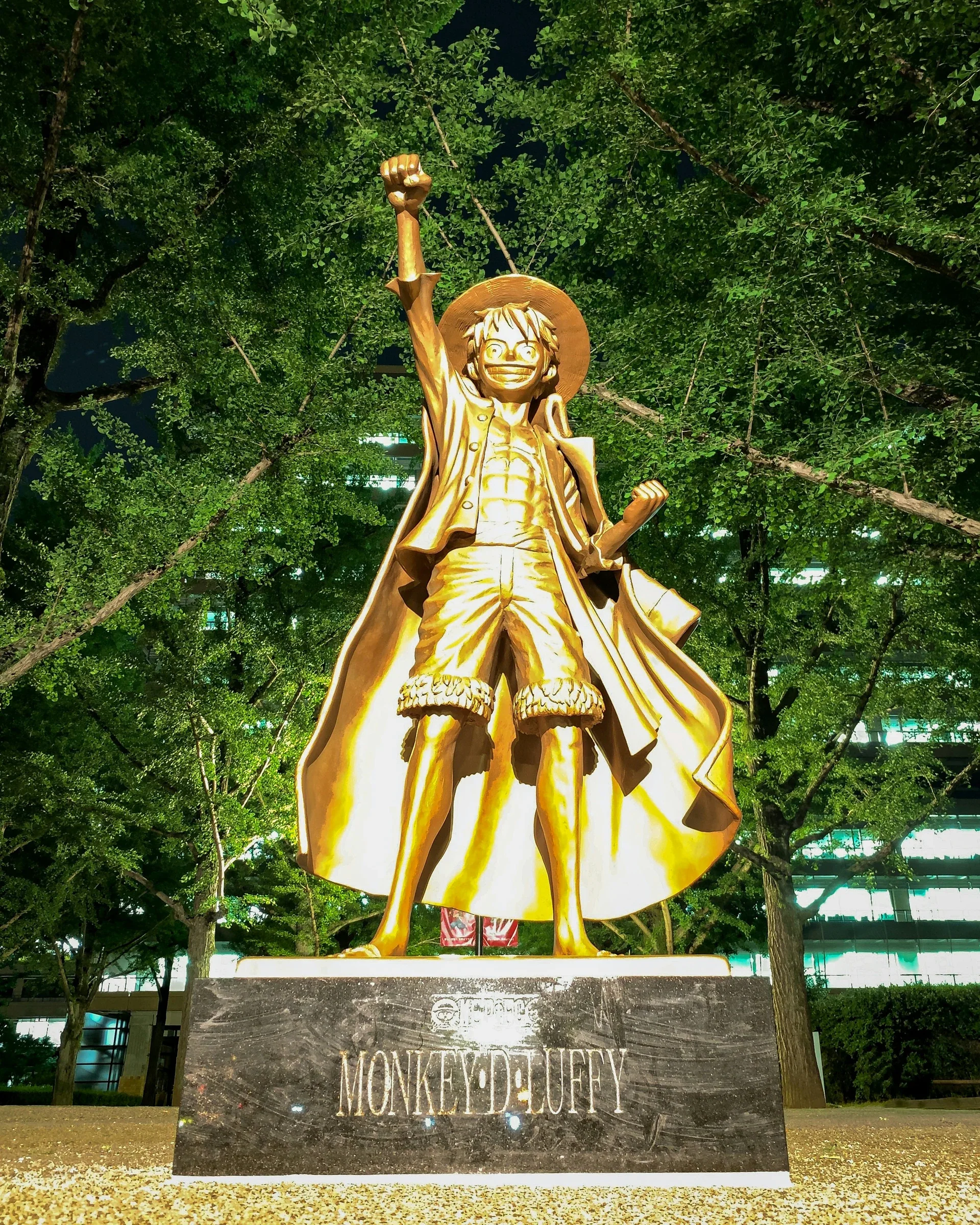 熊本縣廳前的魯夫銅像，高舉手臂站在綠樹之間