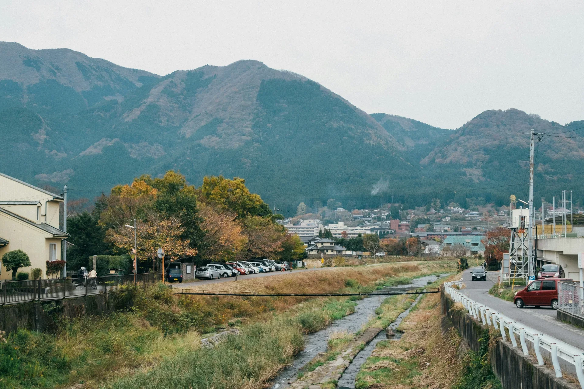 由布院周邊山巒和鄉間聚落，山腳道路穿過綠色田野