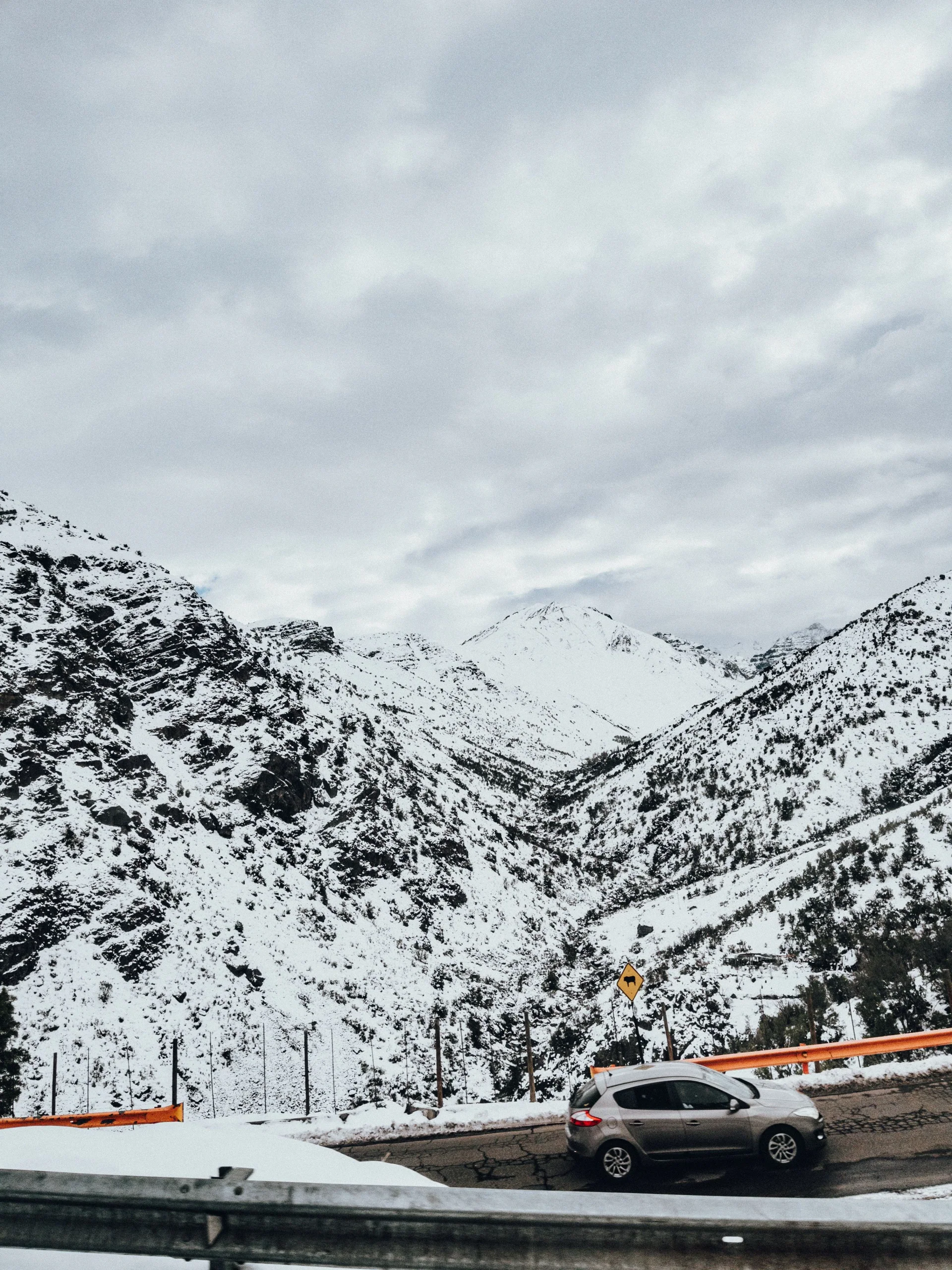 雪山環繞的道路旁停有一輛乘用車