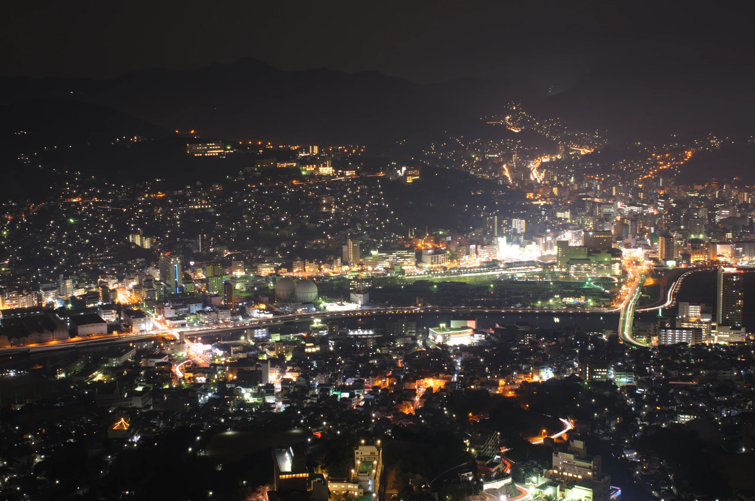 稻佐山展望台望向長崎市區的夜景，沿山坡延伸的住宅燈光映照港口